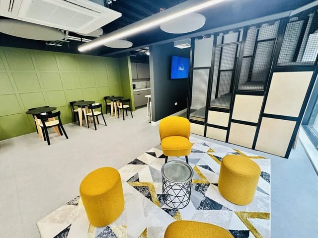 Yellow chairs stools rug tables and wall paneling common area at The Nest Leicester in Leicester Student Accommodation