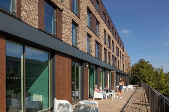 Students relaxing on balcony with modern building exterior at Graystacks in Nottingham Student Accommodation