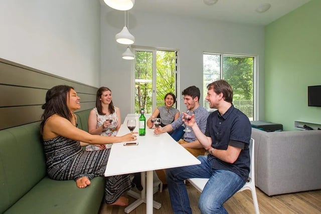 Five friends drinking wine at a table living room at Graystacks in Nottingham Student Accommodation