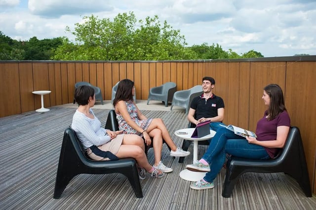 Four students on chairs at a wooden deck playing area at Graystacks in Nottingham Student Accommodation