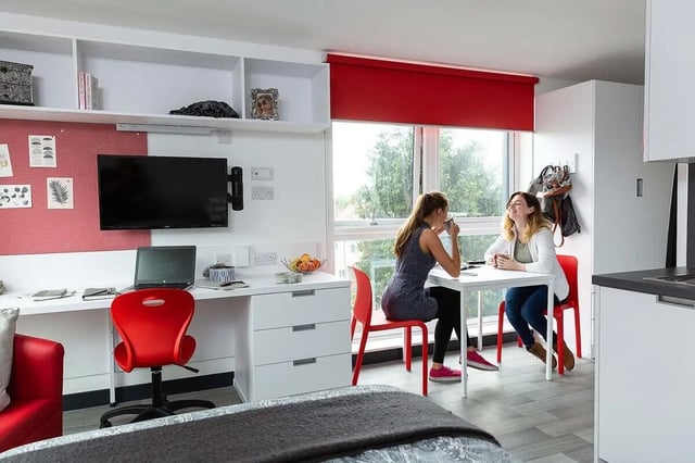 Desk TV laptop red chair two women kitchen living area at Abbey House in Coventry Student Accommodation