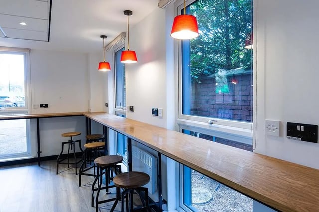 Wooden counter with stools under red pendant lights communal area at Abbey House in Coventry Student Accommodation