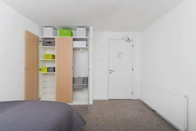 Open wardrobe with green boxes and grey bed bedroom at Froghall in Aberdeen Student Accommodation