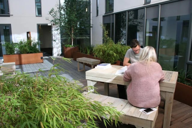Two students studying at a wooden table outdoors study area at CityBlock Penny Street in Lancaster Student Accommodation