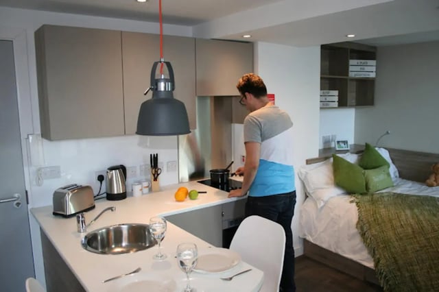 Man cooking in kitchen next to bed studio apartment at CityBlock Penny Street in Lancaster Student Accommodation