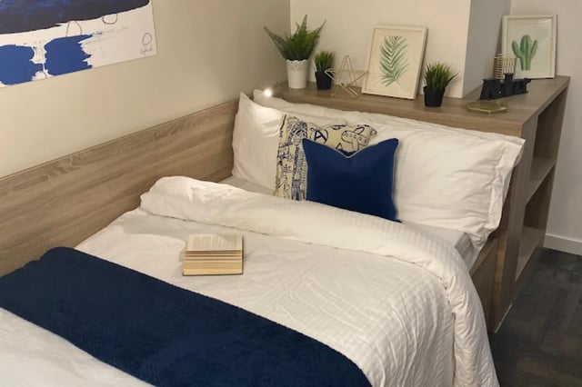 Bed with blue pillows and book bedroom area at CityBlock Penny Street in Lancaster Student Accommodation