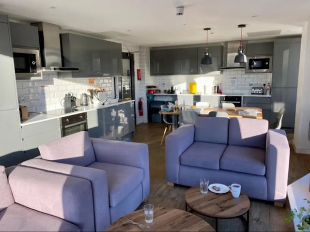 Two sofas kitchen area and dining table living room at CityBlock Marton Street in Lancaster Student Accommodation