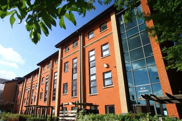 Orange brick building with multiple windows exterior at Ladybarn House in Manchester Student Accommodation