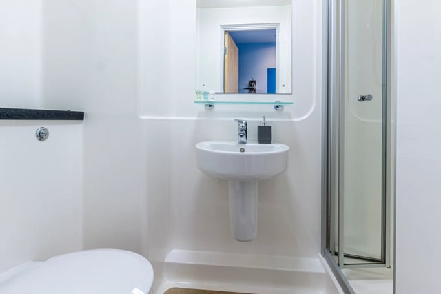 White sink, toilet, shower enclosure, mirror, bathroom at Kaplan Living Glasgow - Old Dumbarton Road in Glasgow Student Accommodation