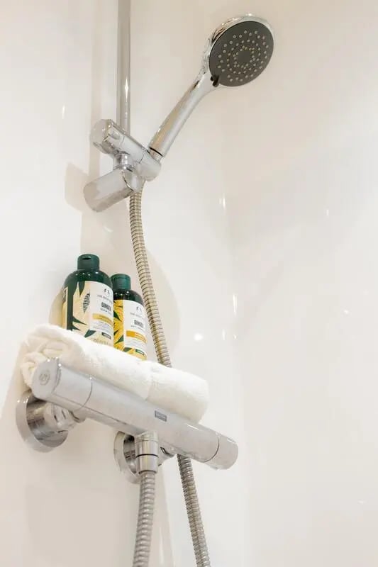Showerhead bottles and towel in bathroom at Trapezium in Leeds Student Accommodation