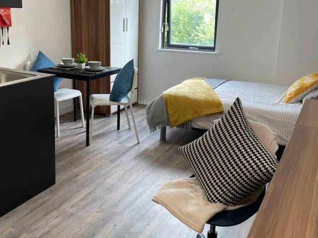 Bed table and chairs with kitchen area Bedroom at Austin Hall in Leeds Student Accommodation