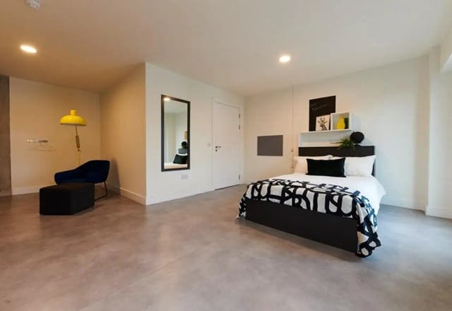 Bed with black white blanket black chair ottoman bedroom at Dorset Point in Dublin Student Accommodation