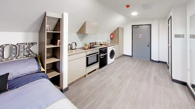 Bed with OK sign and kitchen area studio apartment at Sycamore House in Leeds Student Accommodation