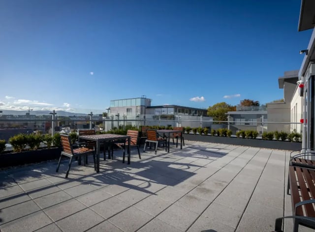 Tables and chairs on a paved rooftop patio area at Highlight Thomas Street in Dublin Student Accommodation