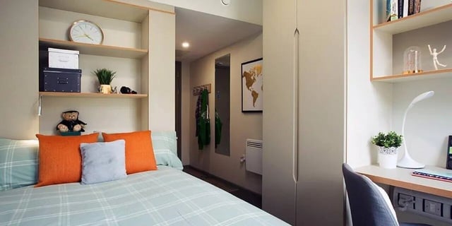 Bed with pillows teddy bear shelf clock bedroom at Liv Dublin in Dublin Student Accommodation