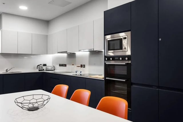 Modern dark blue and white kitchen with orange chairs Kitchen at Highfield House in Dublin Student Accommodation