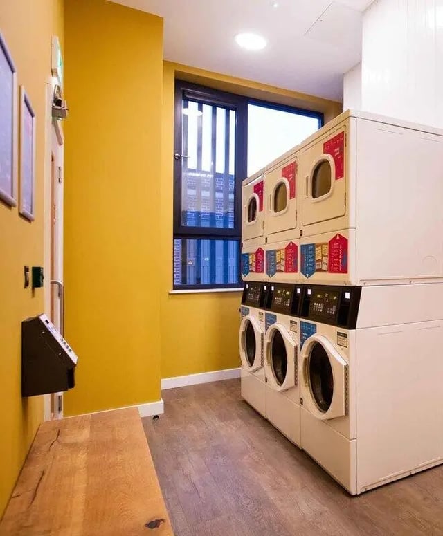 Stacked dryers and washers with payment machine laundry room at Highfield House in Dublin Student Accommodation