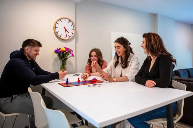 Four students playing board game at table living room at The Westwood in Galway Student Accommodation