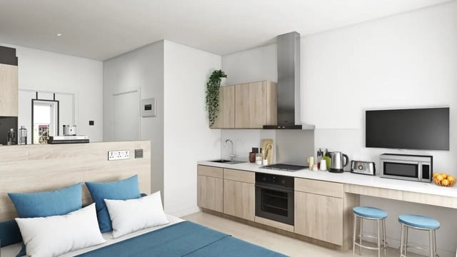 Bed with blue pillows kitchen area living room at Ashlin House in Cork Student Accommodation