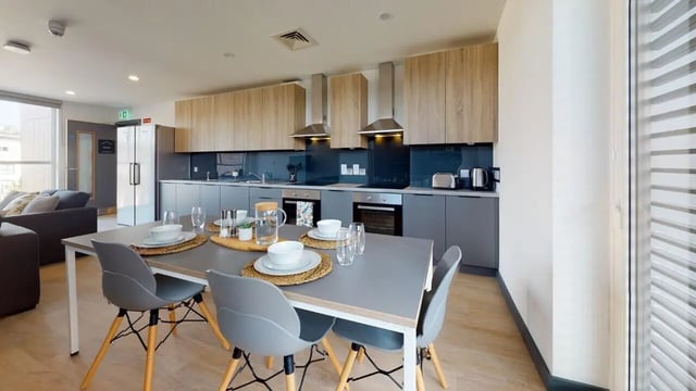 Dining table chairs kitchen cabinets and appliances kitchen at Curraheen Point in Cork Student Accommodation
