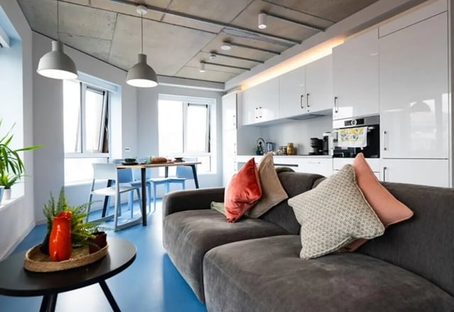 Sofa dining table kitchen white cabinets living room at Stephen's Quarter in Dublin Student Accommodation