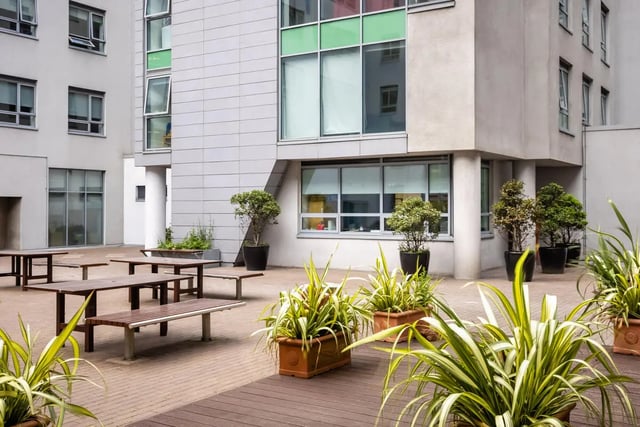 Wooden tables and benches with potted plants exterior at Mayor Square in Dublin Student Accommodation