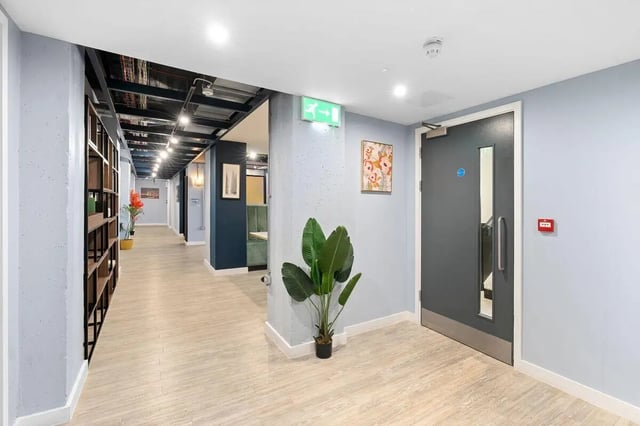 Hallway with bookshelves plant and doorway hallway interior at Pennine House in Leeds Student Accommodation