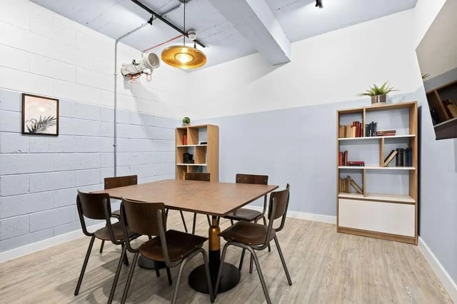 Table chairs bookshelves with books community area at Pennine House in Leeds Student Accommodation