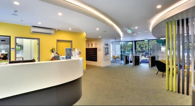 Reception desk with yellow wall and seating area lobby at Scape Glebe in Sydney Student Accommodation