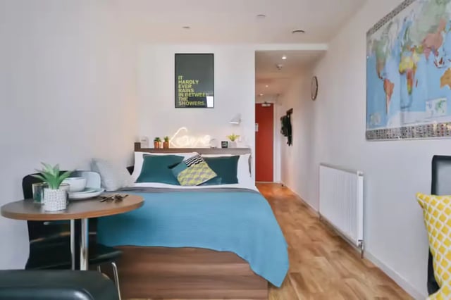 Bed with blue blanket small table and map bedroom at Centro Court in Aberdeen Student Accommodation
