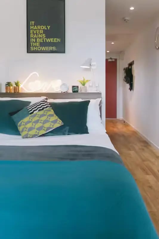 Bed with teal bedding artwork and neon sign bedroom at Centro Court in Aberdeen Student Accommodation