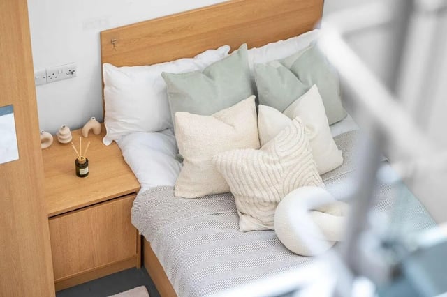 Bed with multiple pillows and bedside table Bedroom at Algernon Firth in Leeds Student Accommodation