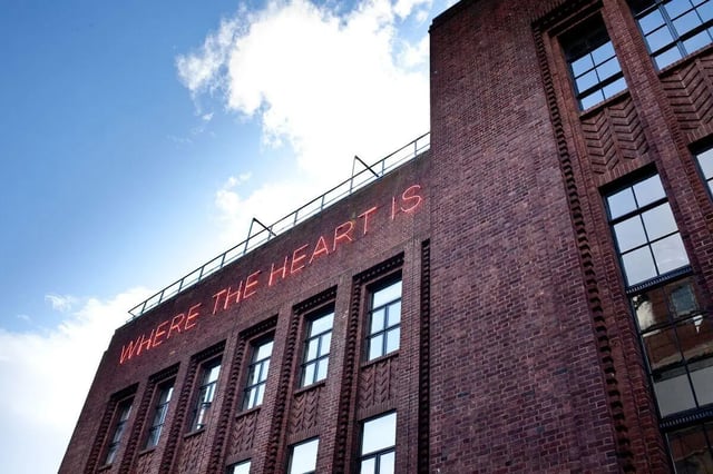 Red neon text on brick building exterior at Algernon Firth in Leeds Student Accommodation