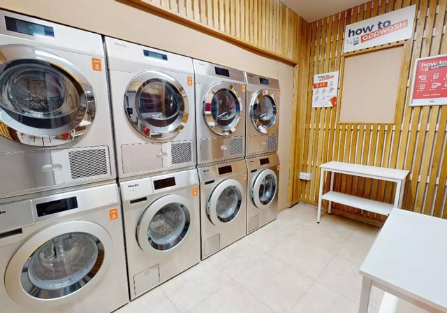 Washing machines dryers and white shelving laundry room at iQ Lambert & Fairfield House in Manchester Student Accommodation