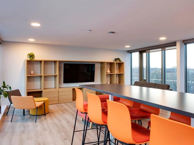 Orange chairs at counter with TV and shelves living room at Brickworks in Dublin Student Accommodation