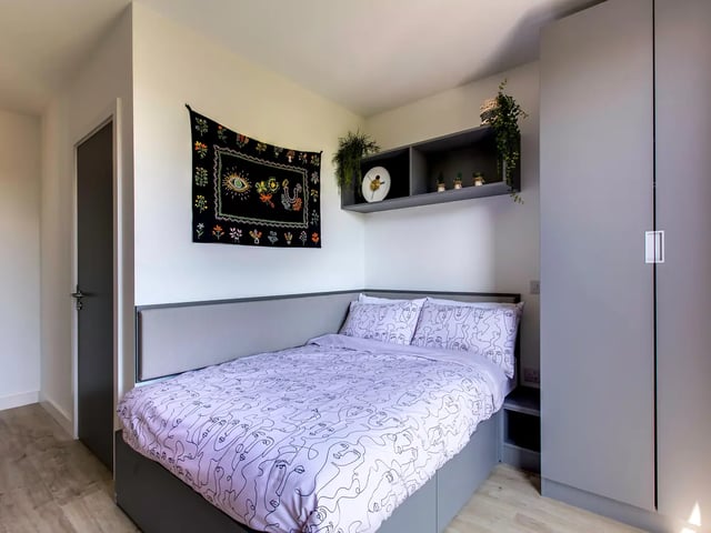 Bed with patterned bedding tapestry shelves bedroom at Lee Point in Cork Student Accommodation