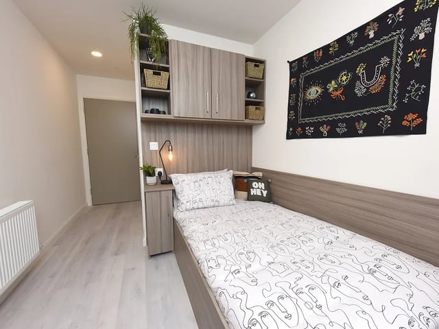 Bed with face print duvet shelving and tapestry bedroom at Melbourn Point in Cork Student Accommodation