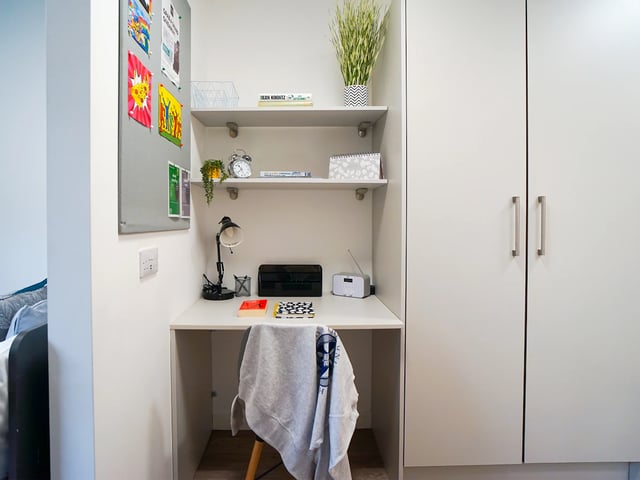 Desk with lamp clock books and shelves study area at Goods Corner in Edinburgh Student Accommodation