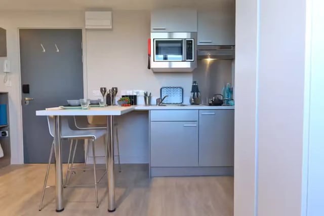 Table with chairs microwave and kitchen cabinets kitchen at Metrovick House in Newcastle Upon Tyne Student Accommodation