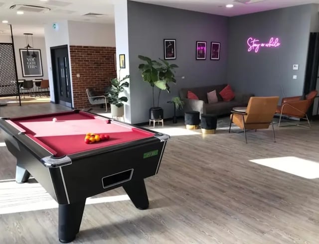 Pool table sofas chairs and neon sign lounge at Little Patrick Street in Belfast Student Accommodation