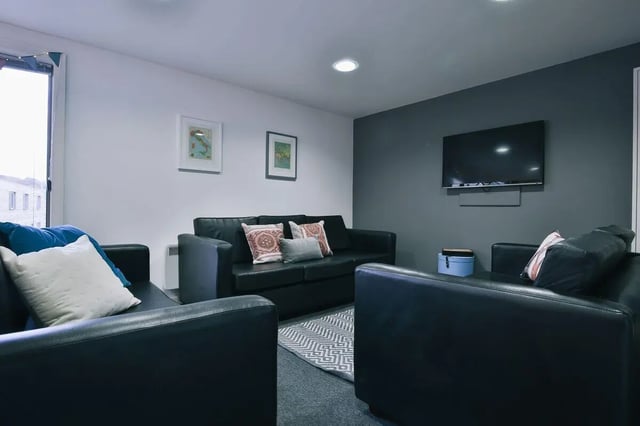 Black leather couches framed by pillows living room at Victoria Court in Lancaster Student Accommodation