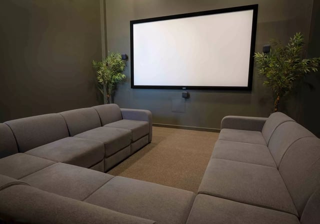 Gray sectional couches facing large projector screen playing area at iQ Astor House in Plymouth Student Accommodation