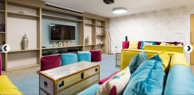 Bright sofas, ottomans, chest, shelves, TV living room at Lilian Knowles House in London Student Accommodation
