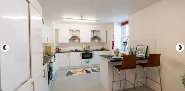 White kitchen cabinets oven and bar stools kitchen at The Craft Building in London Student Accommodation