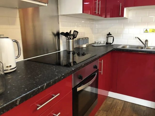 Red cabinets induction hob oven and sink kitchen at Waterside Court in Chester Student Accommodation