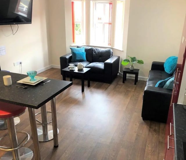Black sofas and bar with table and stools living room at Waterside Court in Chester Student Accommodation