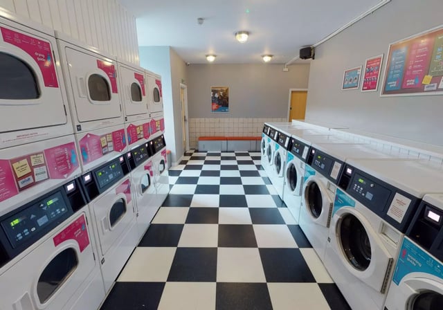 Washing and drying machines along checkered floor laundry room at iQ Fenton House in Sheffield Student Accommodation