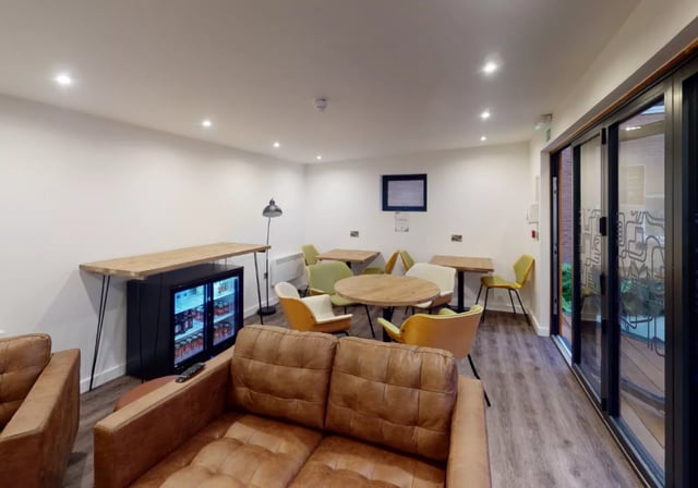 Leather sofas tables chairs and drinks fridge communal area at iQ Great Newton House in Liverpool Student Accommodation