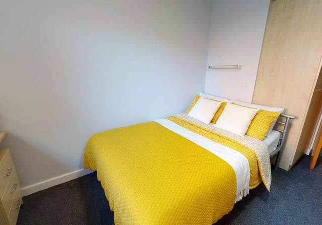 Bed with yellow blanket two pillows white sheets bedroom at iQ Great Newton House in Liverpool Student Accommodation