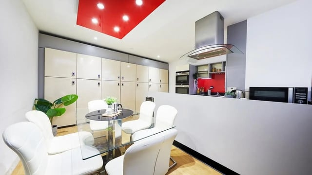 Table with white chairs large cabinets kitchen area at Corporation Village in Coventry Student Accommodation